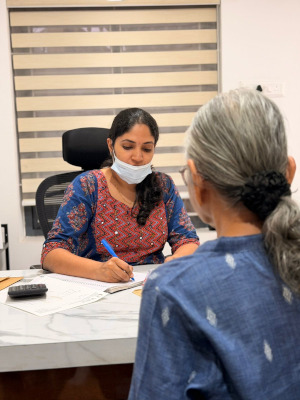 Dr. Liya taking notes during a detailed and friendly dental consultation with a patient at her desk inside Yoha Dental Clinic.