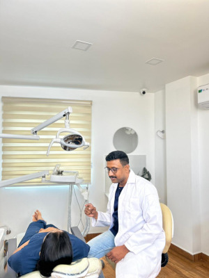 Dr. Thomas Issac having a friendly dental consultation with a patient in a bright, modern treatment room at Yoha Dental Clinic.